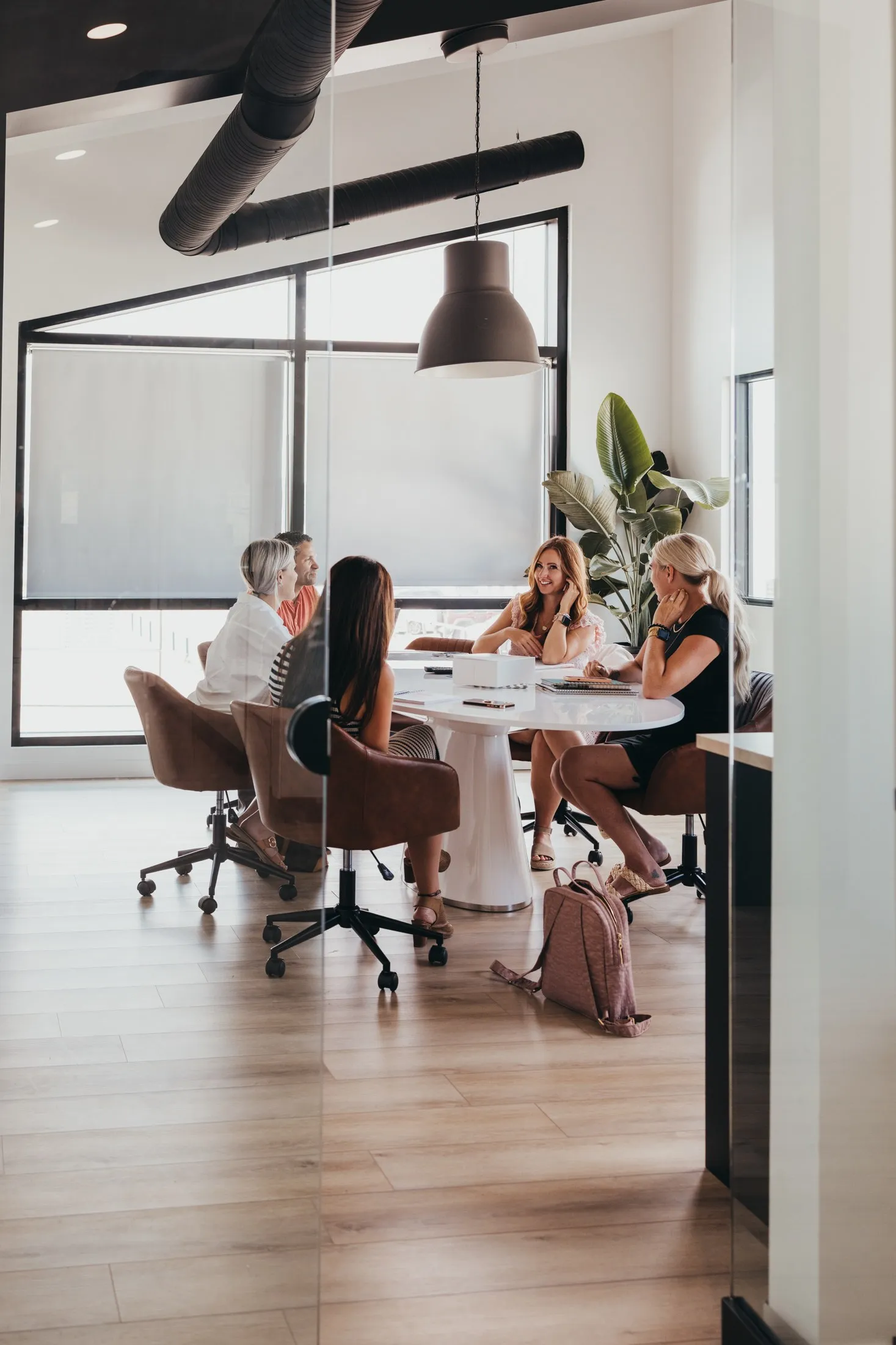 A meeting around the boardroom table, seen through the glass wall