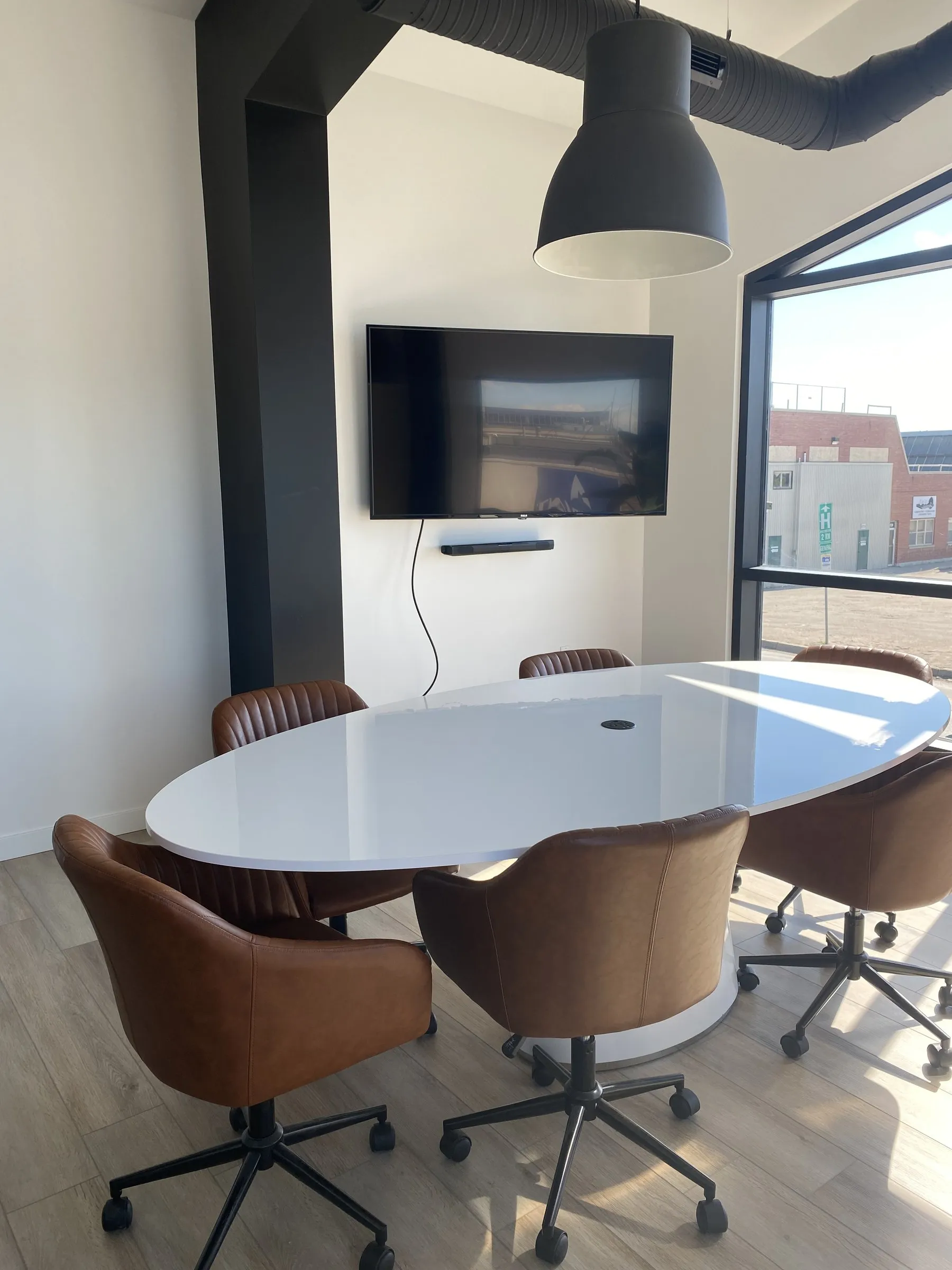 The far end of the boardroom, the screen on the wall and the black window frame