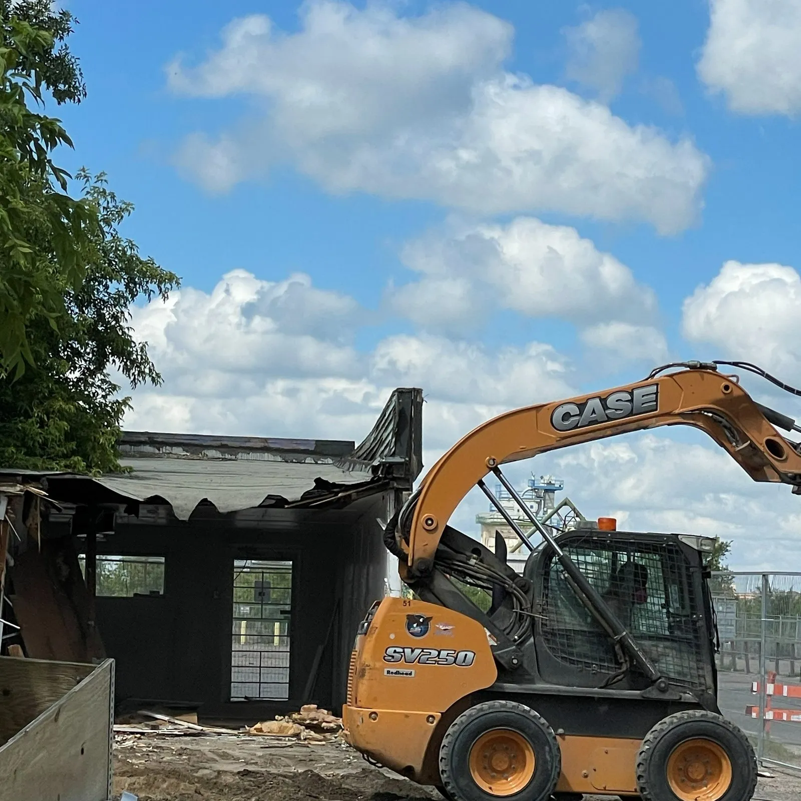 The old building coming down in 2021, a skid steer working beside its broken roof